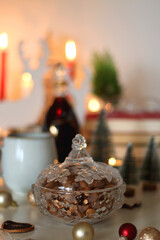 Cookie jar, tea, wine, nuts, books, lit candles and Christmas decorations on the table. Cozy Christmas hygge at home. Selective focus.