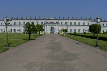 Obraz premium long white religious court building of 'nizamat imambara' with arched gateway, garden path, and heritage lamps at murshidabad, india