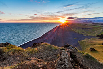 Stunningly beautiful sunset over the ocean as seen from the cape cliffs near the lighthouse of Vik, small city in Southern Iceland, travel tourist destination and sightseeing