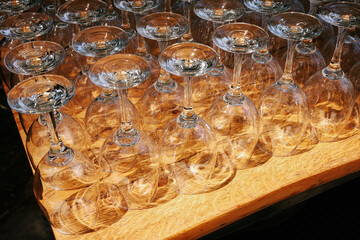 Rows of clean empty wine glasses arrange on a wooden table