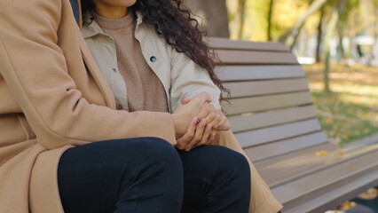Romantic date in autumn park unrecognizable couple cuddling holding hands relaxing on bench in...