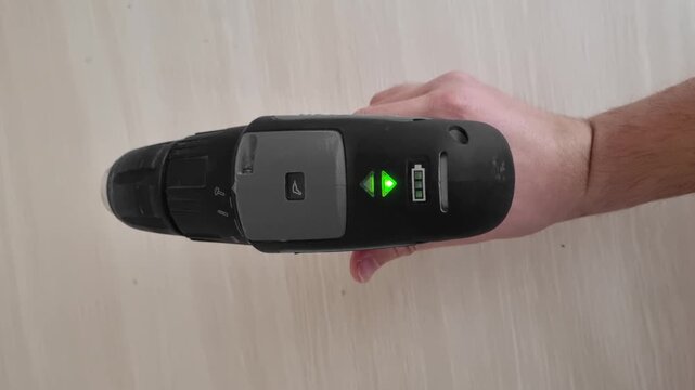 Close up view of a hand operating the rotation direction switch of a cordless power drill changing from screwing to unscrewing mode