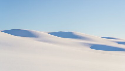 Softly lit snow dunes under a clear blue sky