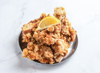 Crispy fried chicken with lemon wedge is perfect for satisfying comfort food cravings and takeout menus, ready to eat on a marble table