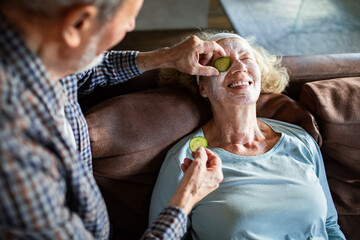 Senior husband and wife enjoying playful home spa on couch