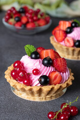 Homemade shortbread baskets with cream and fresh berries on gray background