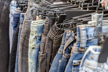 A collection of jeans in various colors and styles displayed on hangers, showcasing denim fashion choices in a retail setting.