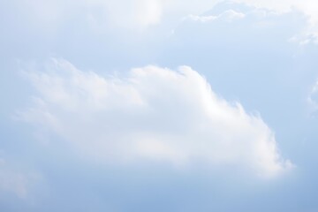 A single fluffy white cloud against a soft blue sky