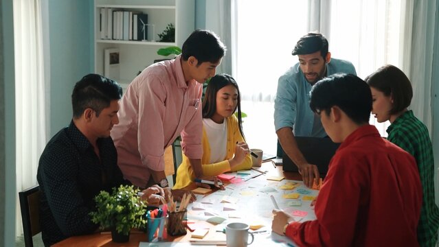Top view of diverse business people drawing mind map by using marker while brainstorm idea and writing on sticky notes. Group of smart team sharing idea while planning creative strategy. Convocation.