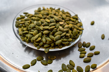 Shelled pumpkin seeds close-up on a small plate – healthy snack concept