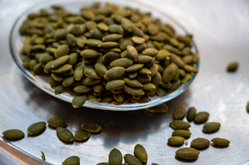 Shelled pumpkin seeds close-up on a small plate – healthy snack concept