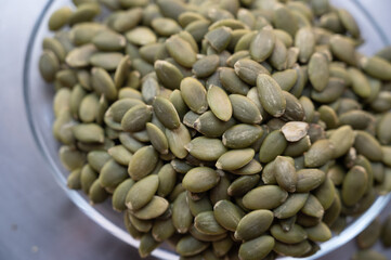 Shelled pumpkin seeds close-up on a small plate – healthy snack concept