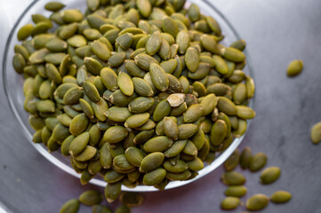 Shelled pumpkin seeds close-up on a small plate – healthy snack concept