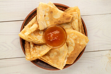 Hot pancakes with apricot jam on a wooden table, macro, top view.