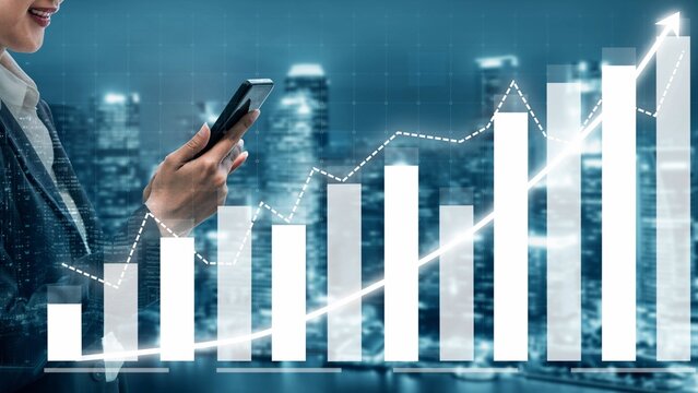 A businesswoman interacts with her smartphone while observing rising financial graphs and data trends in a busy city, symbolizing growth and opportunity. Copula