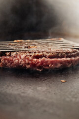 Close-up shot of grilled meat cooking on a hot barbecue grill with a metal spatula lifting the juicy, perfectly seared pieces.