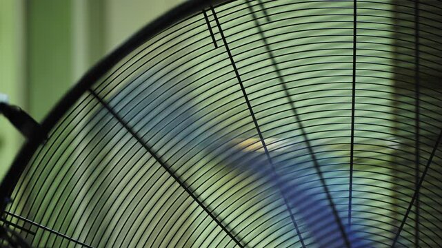 Electric fan grille cooling air in motion, blurred green background