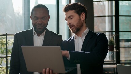 Diverse business team men colleagues cooperation with laptop online internet using web cyberspace work in office talking partners multiracial businessmen discuss corporate success project technology