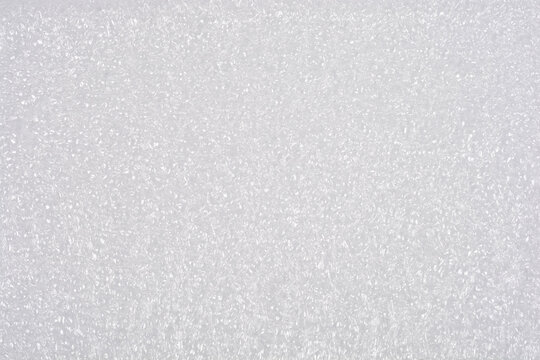 A macro close-up captures the uniform, textured surface of a piece of light grey or white foam packaging material