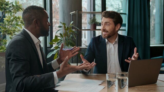 Two multiracial businessmen business team with laptop talking men salesman agent consult male client investor office partners diversity workers negotiation happy satisfied good news investment sales