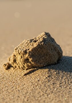 Abstract macro shot showing a dense, textured lump of sand and beach detritus under harsh summer sun, symbolizing heat and heavy density, earth, cluster, surface
