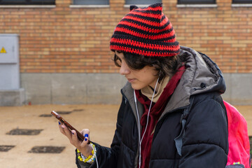 Teenager wearing cat ear hat using phone outdoors
