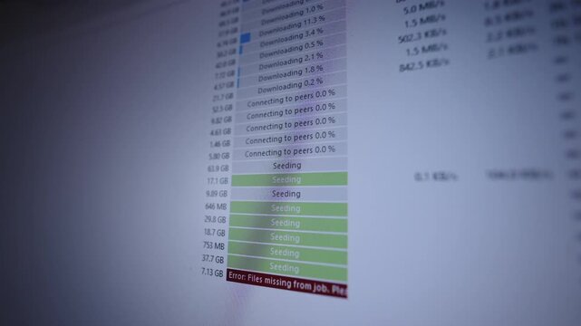 Close-up of computer screen showing torrent client seeding and downloading with progress bars and prominent red missing files error, evoking network issues, data loss and troubleshooting, slow motion.