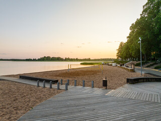 Peaceful evening at Tamula Lake beach in V&otilde;ru, Estonia. Wooden boardwalk, volleyball court, and calm golden sunset over still water. 
