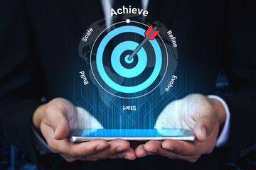A business professional presents a smartphone with a digital target graphic, symbolizing achievement, strategy, and innovative approaches in the modern workplace. Gantry