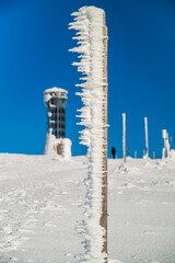 Winter trail on Śnieżnik Mountain with frost-covered poles and lookout tower&rdquo;
