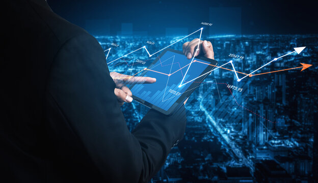 A business professional interacts with data trends on a tablet device at night, showcasing urban city lights and graphical overlays that represent financial insights. Scalp - Powered by Adobe