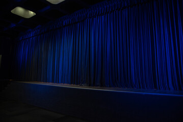 Closed blue theater curtain with dramatic stage lighting
