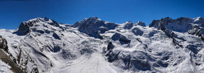 panoramic drone view of snowy alpine mountains and glaciers in winter Switzerland. Wide landscape with dramatic peaks, deep valleys, and untouched snow