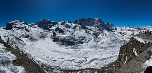 panoramic drone view of snowy alpine mountains and glaciers in winter Switzerland. Wide landscape with dramatic peaks, deep valleys, and untouched snow