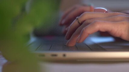 A woman's hands typing on a laptop keyboard in an office, doing copywriting, writing articles, or creating stories for social media. A close-up of a computer keyboard and a person typing. - Powered by Adobe