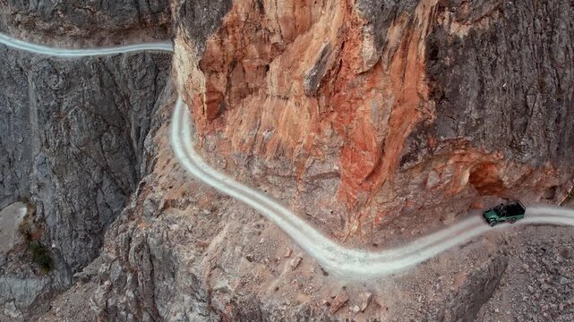 A narrow cliffside road winds along the steep rocky walls of Kemaliye Canyon, following the river flowing below. The dramatic terrain, rugged cliffs and elevated path create a striking canyon landscap