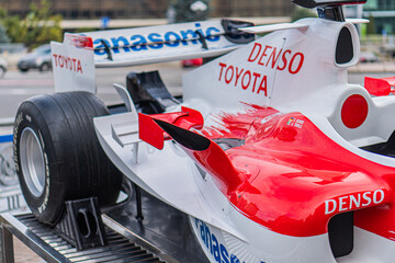 Obraz premium White, red, black Formula 1 Toyota TF-108 car parked on tarmac or transport surface, AON and DENSO TOYOTA logos, urban setting hints, daylight photography with long - Kyiv, Ukraine 10-10-2024