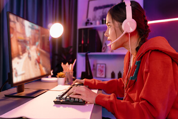 Host channel of young beautiful Asian gaming streamer, playing battle team gaming with multiplayer or single at warship on screen, wearing pastel color headset at digital neon light room. Stratagem.