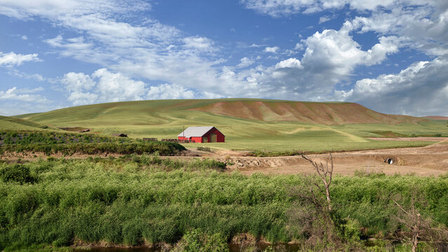 Distant Red Structure on Rolling Hills at Golden Light