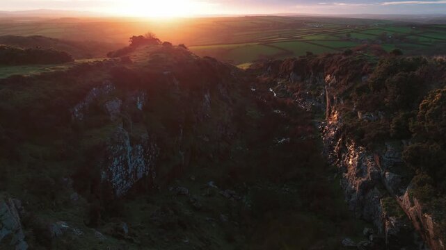 Aerial view of rugged hillsides leading to verdant fields under a warm sunset glow, casting shadows and highlighting textures, Bodmin, England, United Kingdom.