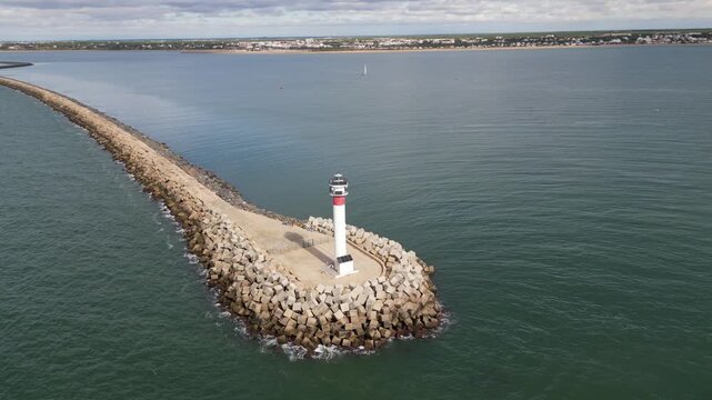Aerial view of Faro de El Espigon lighthouse standing tall against the tranquil sea, a beacon of light, Huelva, Andalusia, Spain.