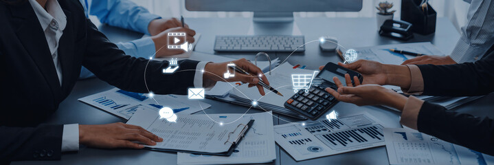 Business professionals collaborate in an office setting, using calculators and smartphones for...