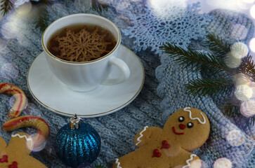 A cup of tea with a decorative snowflake on a blue knitted item