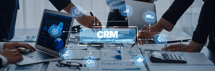 A modern business meeting showcases teamwork around customer relationship management tools. Laptops...