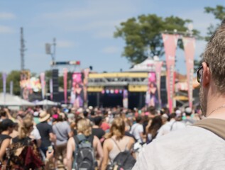 Obraz premium Grande foule devant une scène musicale jaune animée en plein air, festival estival français avec arbres et drapeau tricolore. 