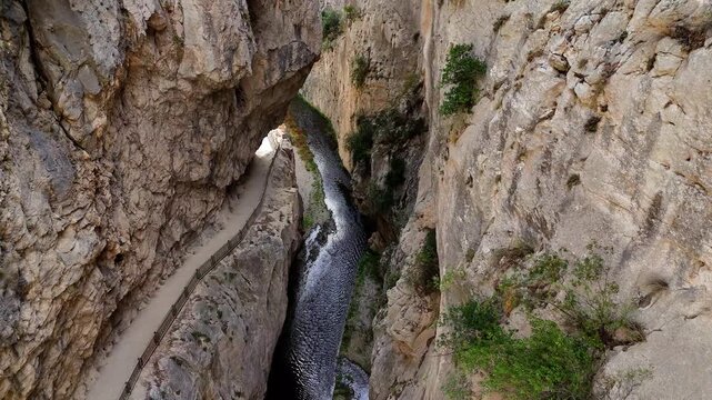 Breathtaking high angle view looking down into the narrow gaitanes gorge, showing the famous caminito del rey hiking trail and the guadalhorce river