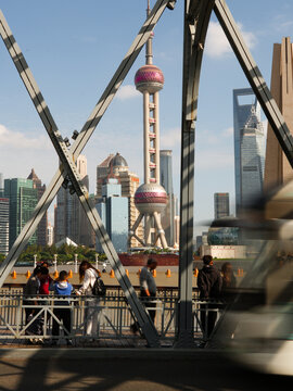 Shanghai, China - 25 October 2025: View of the Oriental Pearl Tower framed by the intricate metalwork of a bridge, with city buildings and blurred vehicles.
