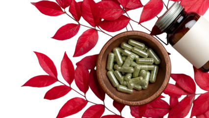 PNG of Aesthetic close-up of green herbal capsules in a wooden bowl, surrounded by vibrant autumn leaves and a glass bottle.