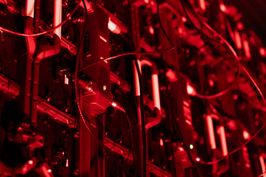 Large grid of vertically oriented hardware components with extensive cabling and small illuminated points, forming a tightly packed electronic structure