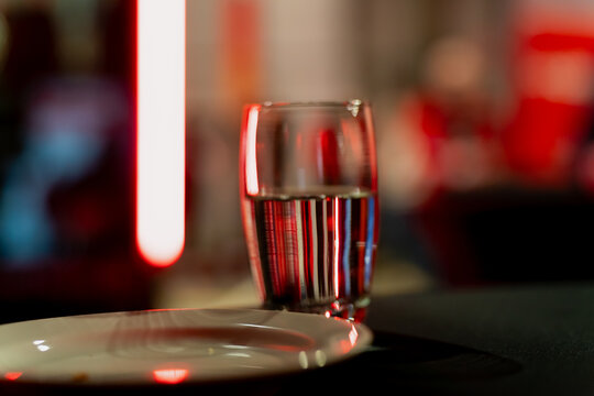 Glass of water and plate set on a table with blurred stage lighting in the background, reflecting the backstage hospitality and working environment typical of modern stage production